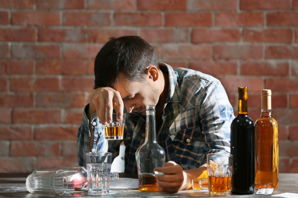 Drunk Man Sitting at Table with Alcohol and Drugs