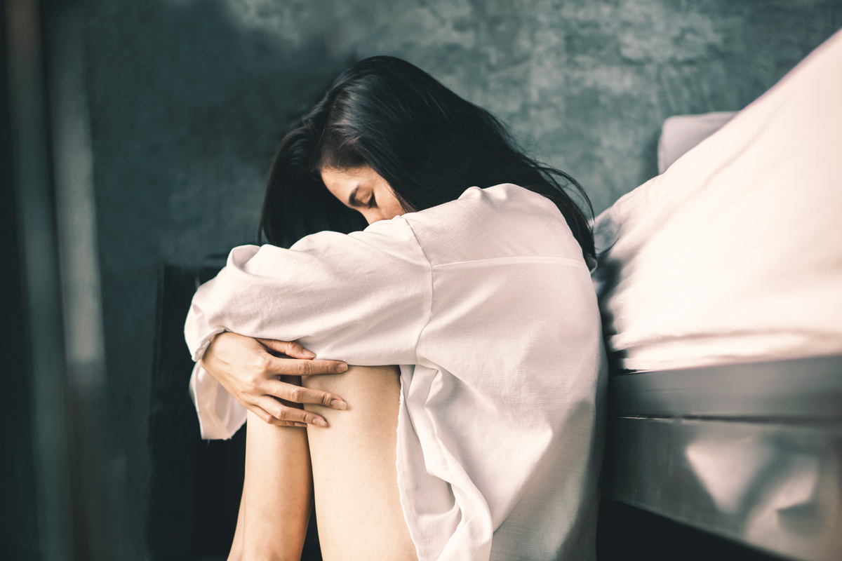 Lonely and Stressed Asian Woman Sitting Alone in Room, Depicting Sadness and Emotional Distress